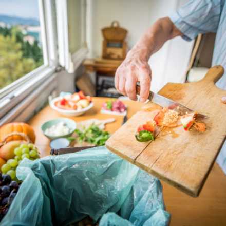 cutting board with veggies and man holding a knife