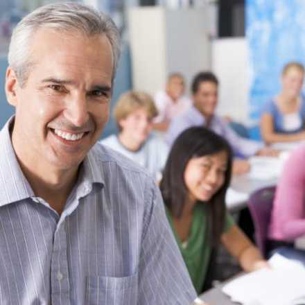 Man smiling in front of a classroom