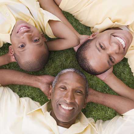 Smiling people family looking up at camera laying on grass