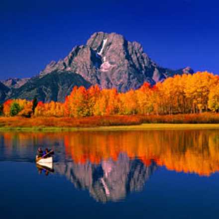 calm Lake with mountains and fall colored forest in the background.