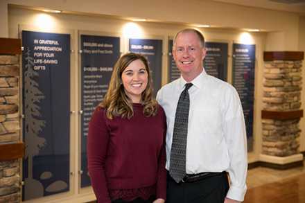 Karli and Jonathan in front of donor wall