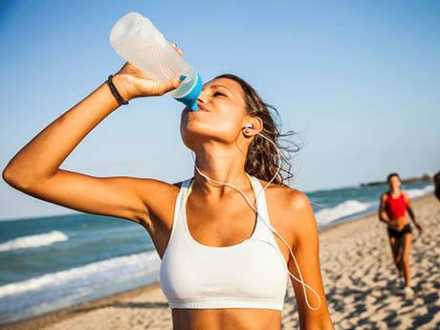 Woman Drinking Water on the Beach