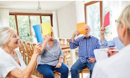 seniors sitting in circle holding colored paper in front of their face