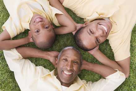 Smiling people family looking up at camera laying on grass