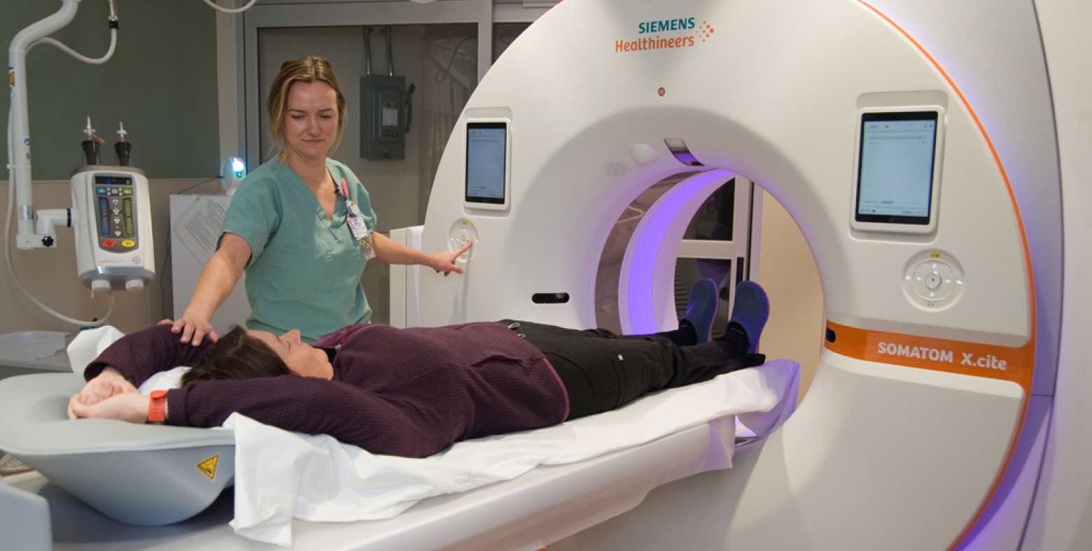 Diagnostic imaging tech with patient and CT scanner