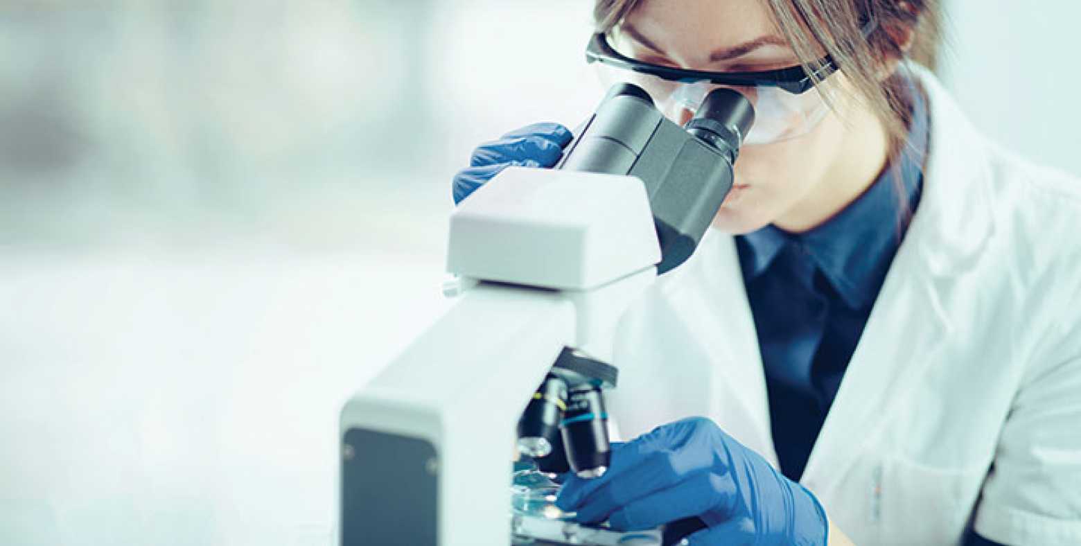 lab technician uses a microscope