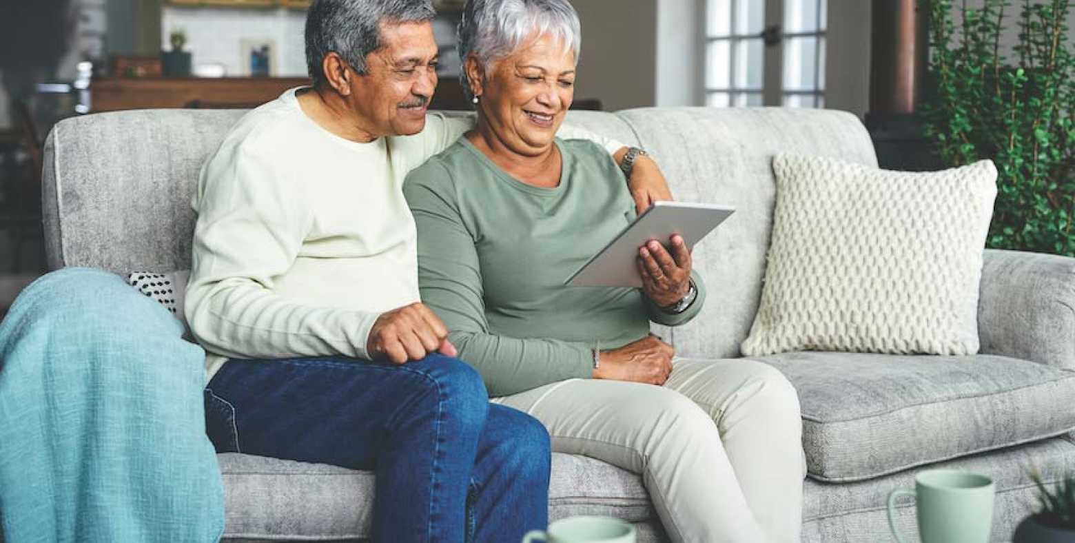 Senior couple looking at a screen on a couch