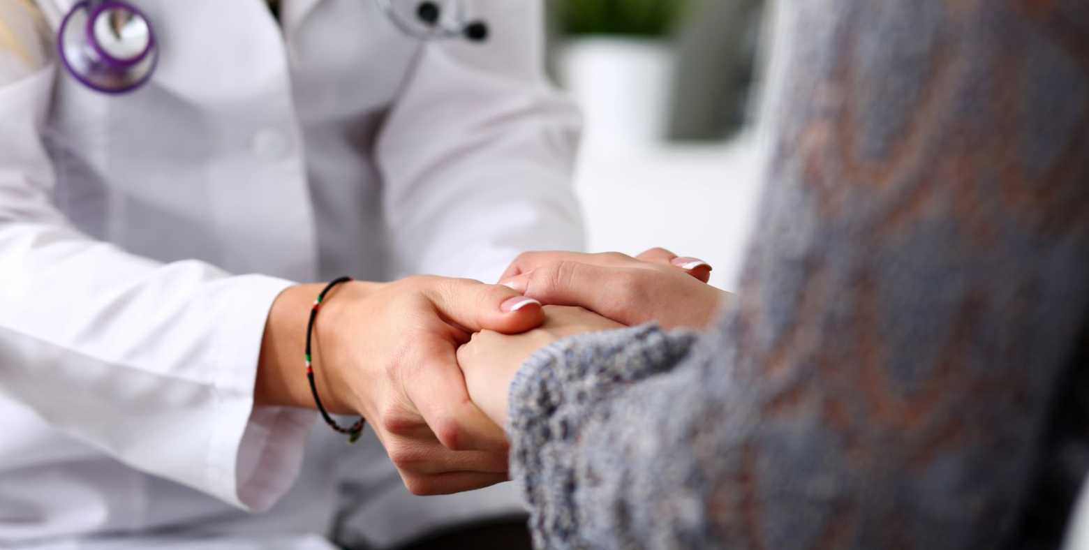 A doctor holds a patient's hands