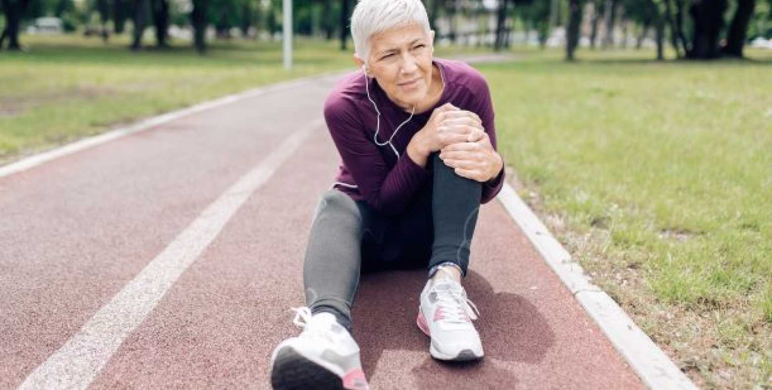 woman sitting on track field holding her knee