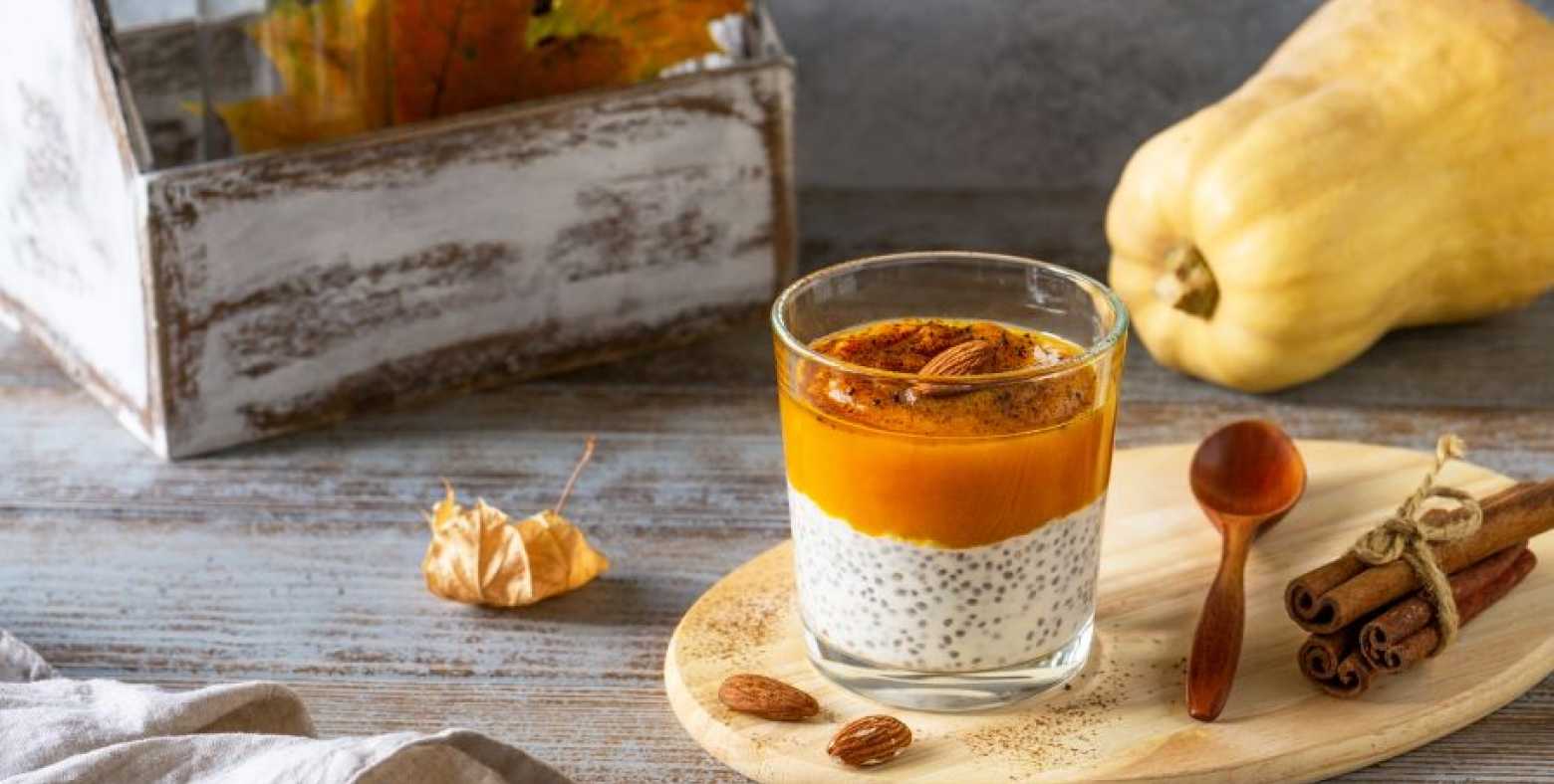 pumpkin chia pudding in a cup with fall decor around  it