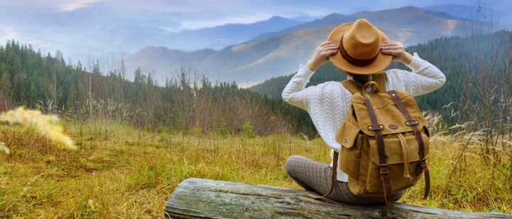 female sitting on log gazing at mountain range