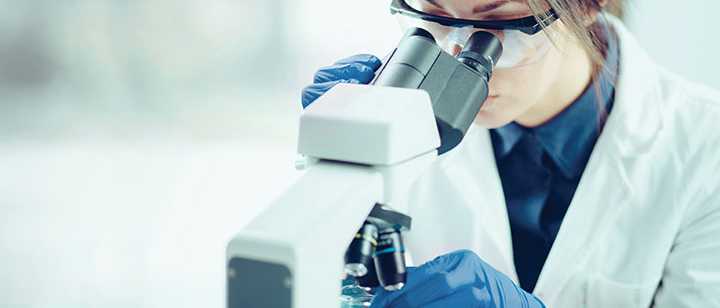 lab technician uses a microscope