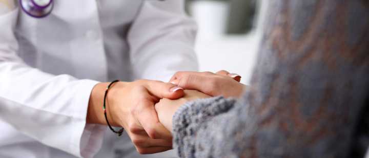 A doctor holds a patient's hands